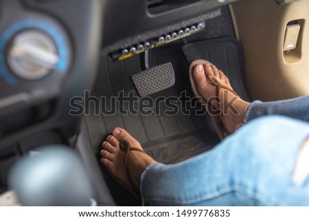 Woman foot driving car with shoe pushing on car speed pedal.
Female feet with brake and accelerator pedals, car speed control concept.