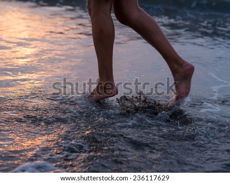 Woman foot on the beach splashing water