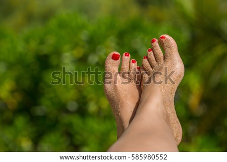Woman foot with red pedicure in the tropical beach conceptual image of vacation