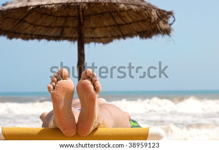 Woman foot with sand on the beach and sea in the background.
