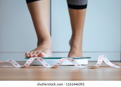 Woman Foot Stepping On Weigh Scales With Tape Measure In Foreground,Body And Good Health Concept,Weight Loss Self-efficacy