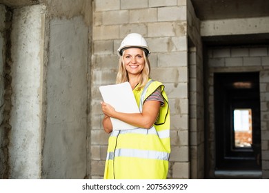 Woman Foreman officer inspector, building Inspector, engineer or inspector at construction site checking and inspecting progressing work in construction site, in hardhat and high-visibility vest