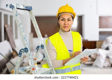 Woman Foreman In A Protective Helmet And Yellow Vest Checks The Completed Construction Work On The Drawing