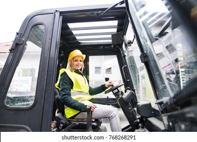 Woman Forklift Truck Driver In An Industrial Area.