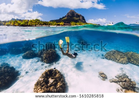 Woman freediver glides over sandy sea with fins in transparent ocean. Freediving in Mauritius