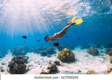 Woman freediver swimming over with yellow fins in blue ocean. Freediving or snorkeling in Mauritius