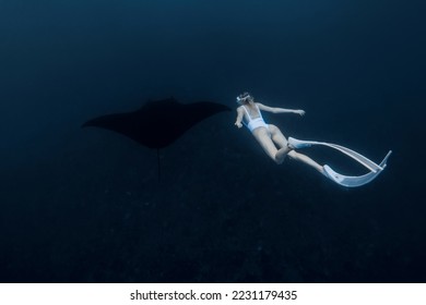 Woman freediver with white fins swim with manta ray. Freediving with big manta ray