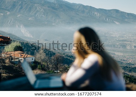 Woman freelancer sits with a laptop outside and looking to Olympic mountains