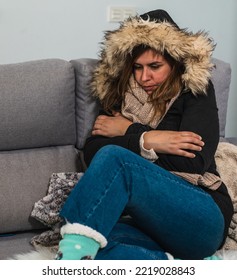 Woman Freezing At Home Wearing A Winter Coat On The Sofa