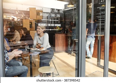 Woman With Friends At A Cafe Seen Through Window