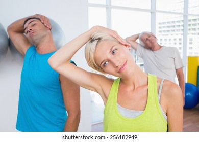 Woman With Friends Doing Neck Exercise In Fitness Club