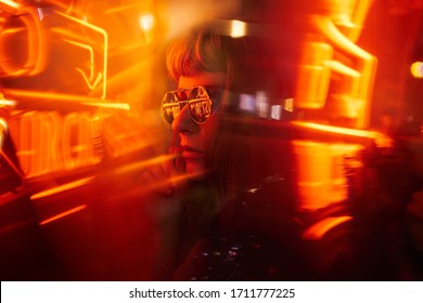 Woman with fringe wearing sunglasses with orange yellow red neon lights