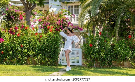 Woman Front Behind Of A Woman Walking Along The River Of A Luxury House With Beautiful Landscaping On A Bright, Sunny Day, Modern Design.