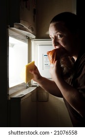 Woman In Front Of The Fridge Eating Chicken