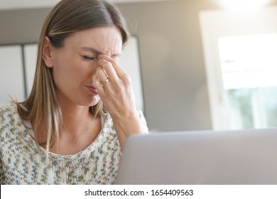 Woman in front of laptop having a headache - Shutterstock ID 1654409563