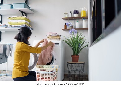 Woman In Front Of The Washing Machine Doing Some Laundry Loading Clothes Inside