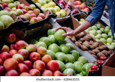 woman in the fruit market with apple in hand. fruits and vegetables. a lot of fruits. market. store. background. citruses. healthy food. natural.. food. health.VEGETARIAN. diet - Shutterstock ID 628463555