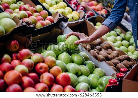 woman in the fruit market with apple in hand. fruits and vegetables. a lot of fruits. market. store. background. citruses. healthy food. natural.. food. health.VEGETARIAN. diet