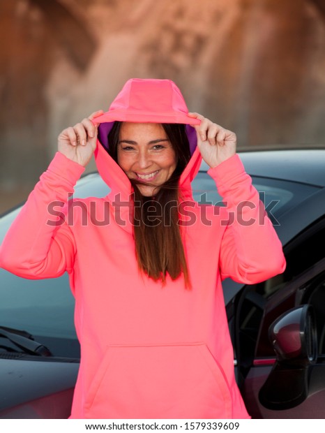 woman with\
fuchsia sweater, next to the gray\
car