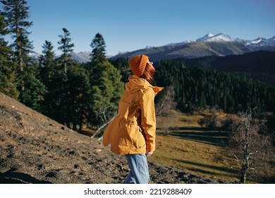 Woman Full Back Hiker Running On The Mountain Looking At Nature Happiness Overlooking Snowy Mountains And Trees In Yellow Raincoat Travel And Hiking In The Mountains At Sunset Freedom