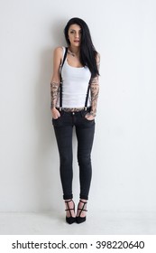 Woman Full Body Portrait With Tattoo Against White Wall Background.