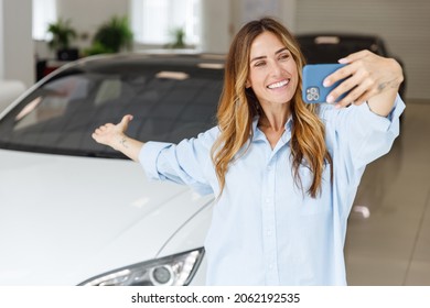 Woman Fun Customer Buyer In Blue Shirt Do Selfie Shot Mobile Cell Phone Point On Car Choose Auto Want To Buy New Automobile In Showroom Vehicle Salon Dealership Store Motor Show Indoor. Sales Concept