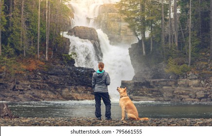 Woman in functional clothing next to loving dog looking at rushing Myra Falls waterfall in Strathcona Provincial Park - Powered by Shutterstock