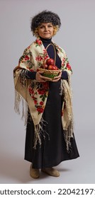 Woman In A Fur Hat And A Colored Shawl With A Basket Of Apples On A White Background