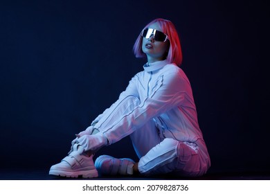 Woman In Futuristic Costume. Female In Modern VR Glasses Interacting With Network While Having Virtual Reality Experience. Augmented Reality Game, Future Technology, AI Concept. VR. Neon Blue Light.