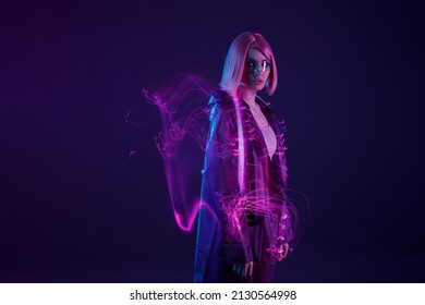 Woman in futuristic costume. Female in modern VR glasses interacting with network while having virtual reality experience. Augmented reality game, future technology, AI concept. VR. Neon purple light. - Shutterstock ID 2130564998