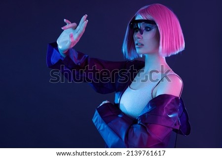Woman in futuristic costume. Female in modern VR glasses interacting with network while having virtual reality experience. Augmented reality game, future technology, AI concept. VR. Neon violet light.