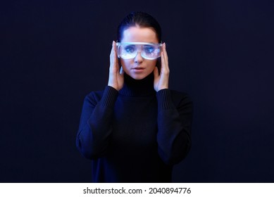 Woman with futuristic tablet in hand. Female using VR glasses. Augmented reality, future technology concept. Blue neon light. Futuristic holographic interface to display data.