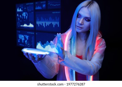 Woman with futuristic tablet in hand. Girl in glasses of virtual reality presses the start button. Augmented reality game, future technology, AI concept. Holographic interface to display data.