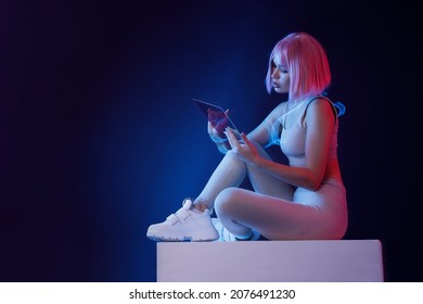 Woman with futuristic tablet in hand. Girl in glasses of virtual reality. Augmented reality, future technology, AI concept. Holographic interface to display data. Dark background.
