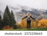 Woman gains energy and improves her mental health from nature in the mountains while hiking in an autumn forest
