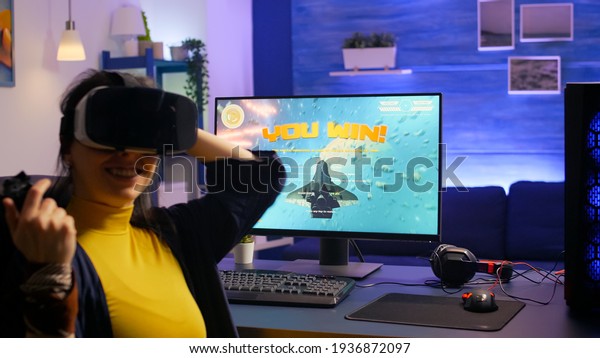 Woman gamer\
winning space shooter video games while wearing vr headset in\
gaming studio. Pro player playing video games during online\
tournament using technology network\
wireless