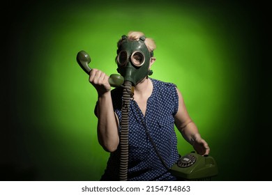 A Woman In A Gas Mask Calls On A Retro Phone On A Dark Dramatic Background, Hard Light