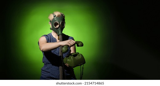 A Woman In A Gas Mask Hangs Up A Retro Phone On A Dark Dramatic Background With Copy Space, Hard Light.