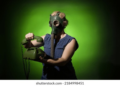 A Woman In A Gas Mask Hangs Up A Retro Phone On A Dark Dramatic Background, Hard Light.