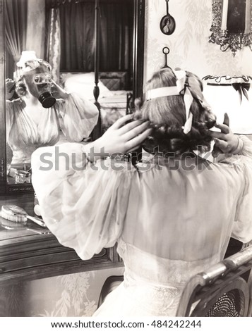 Woman in gas mask looking in mirror