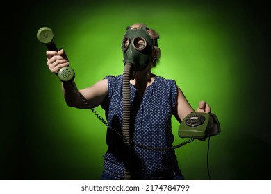 A Woman In A Gas Mask Passes The Receiver Of A Retro Phone On A Dark Dramatic Background, Hard Light.