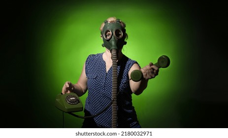 A Woman In A Gas Mask Passes The Receiver Of A Retro Phone On A Dark Dramatic Background, Hard Light.