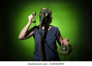 Woman In A Gas Mask Talking On A Retro Phone On A Dark Dramatic Background, Hard Light