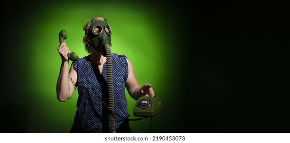 Woman In Gas Mask Talking On Retro Phone On Dark Dramatic Background With Copy Space, Hard Light