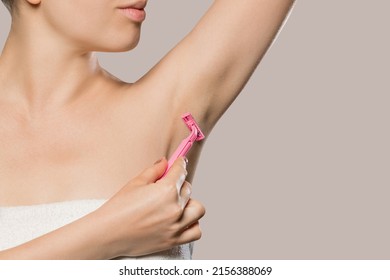 Woman gently shaving armpit epilation hair removal with ergonomic pink shaver. Body care skin care beauty concept.