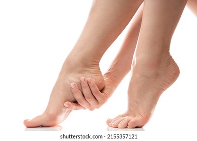 Woman gently touching soft skin of her heel. Closeup of female feet on white background.