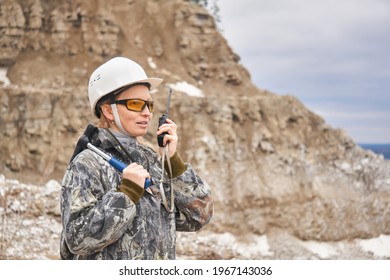 Woman Geologist Talking On The Radio On The Background Of The Slope Of The Quarry