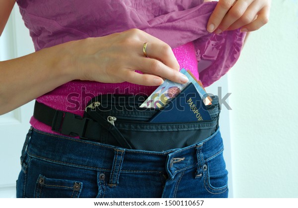 Woman getting cash Euros and passport from
hidden travel money belt she has under her clothes to protect
herself from pickpocket thieves and credit card scanners safely
transporting documents.