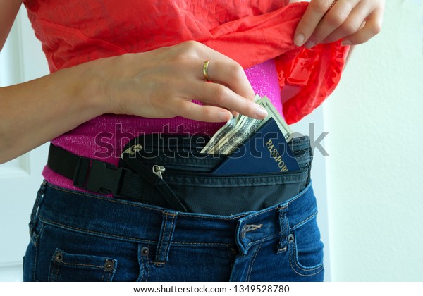Woman getting cash and passport from hidden
travel money belt she has under her clothes to protect herself from
pickpocket thieves and credit card scanners safely transporting
documents in transit.