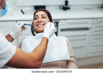 Woman getting a dental treatment at dentistry. Dentist examining the teeth of female patient with tools in clinic. - Powered by Shutterstock